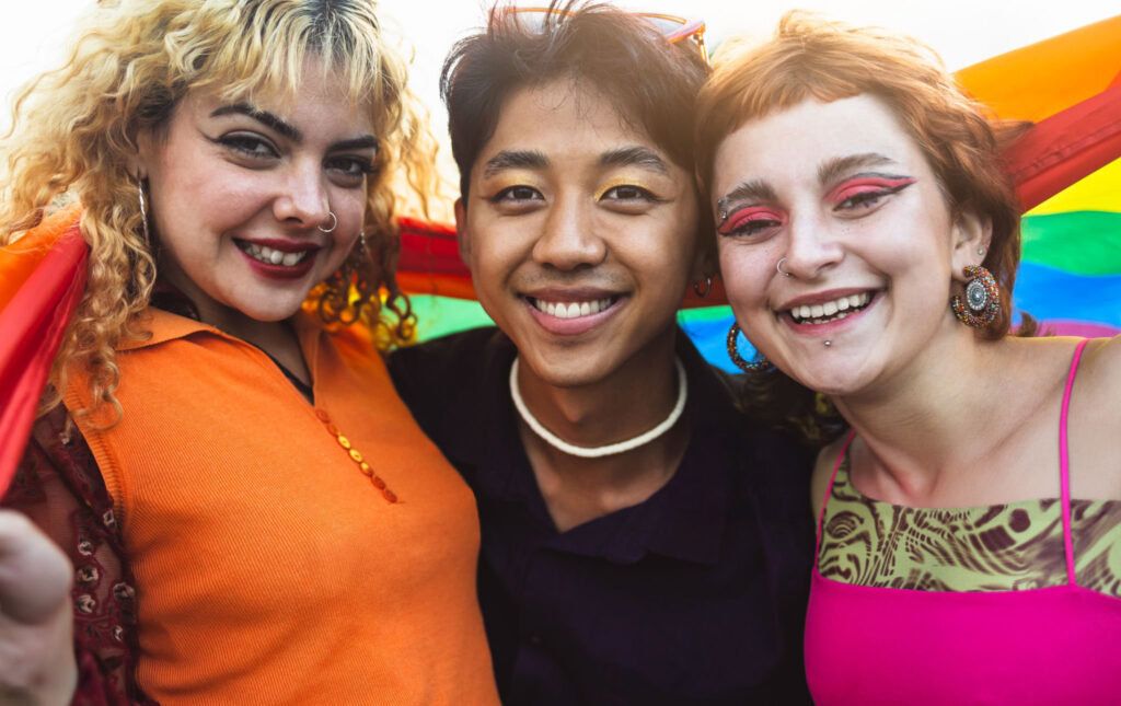three queer youths with a pride flag